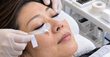 Professional lash extension appointment demonstrating under-eye lash tape placement and lower lash isolation during a beauty salon treatment