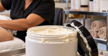 Professional massage cream jar with visible product buildup around the lid and container rim at a spa treatment workstation