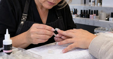 Professional nail tip application troubleshooting showing nail tips and nail adhesive used to prevent premature tip detachment before acrylic or gel enhancements
