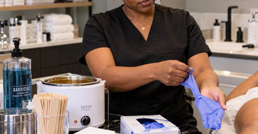Professional waxing gloves and hair removal supplies arranged in a clean spa treatment room