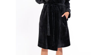 Woman wearing a super soft black plush shawl robe in a spa setting, looking relaxed and comfortable.