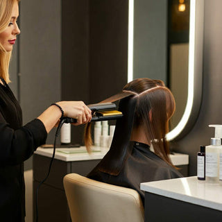 Professional hair stylist performing advanced hair straightening technique in salon