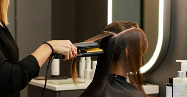 Professional hair stylist performing advanced hair straightening technique in salon