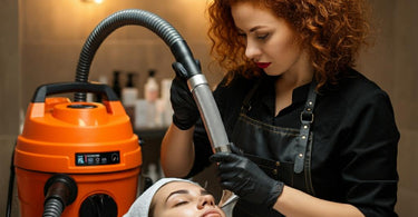 Esthetician humorously using an orange industrial shop vac on a client's face