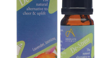 Absolute Aromas De-Stress Aromatherapy Blend 10 mL bottle displayed on a spa table with a diffuser and towel.