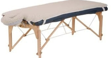 EarthLite Basic Fleece Pad Set on a massage table, featuring the thick white fleece padding and face cradle cover for professional spa comfort.
