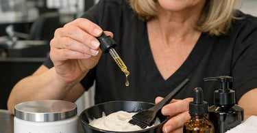 Marula oil being poured into a professional hair mask mixing bowl with a wooden applicator