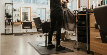 Salon professional standing on an anti-fatigue mat while working