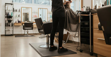 Salon professional standing on an anti-fatigue mat while working