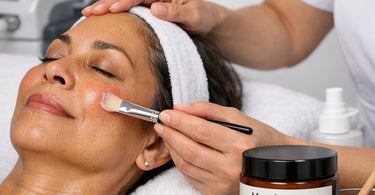 A jar of Manuka honey infused post-laser recovery balm on a spa counter next to a towel and a spatula