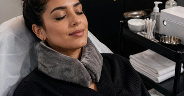 A woman with a warm, plush neck wrap relaxing her shoulders in a serene spa waiting area