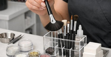 Professional holding a fan brush with sparkling glitter dust against a dark background for salon and spa services
