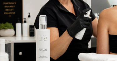 Professional pre-treatment spray bottle being applied to skin for an even spray tan with a smile