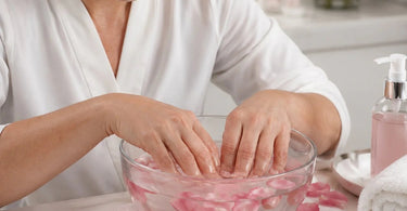 Luxury manicure with a rose water soak, featuring a glass bowl filled with pink water and rose petals for a spa treatment