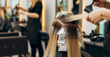 Professional stylist applying bleach to a client's hair in a salon setting