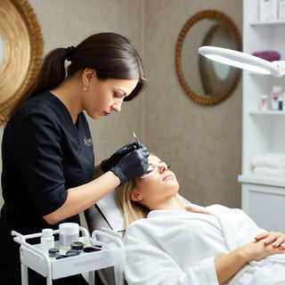 Blonde woman receiving eyelash tinting treatment at a spa