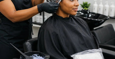 A professional stylist assisting a client with a Colortrak disposable processing cap during a hair color treatment, ensuring comfort and hygiene.