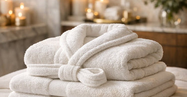 A luxurious spa setting showcasing neatly folded, high-quality white towels and plush robes arranged on a sleek shelf, evoking a sense of calm and professional elegance.