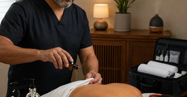 Mobile massage therapist preparing sensory ritual supplies with aromatherapy oils and portable equipment in a client's living room.