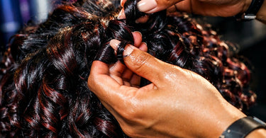 Close-up of a professional hairstylist applying curl defining gel to a client's beautiful, bouncy curls in a salon setting.