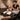 Luxurious modern barber spa shampoo lounge with a client relaxing in a comfortable black reclining chair, warm ambient lighting, and a professional stylist preparing products.