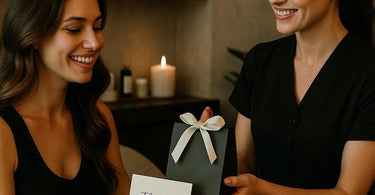 Spa professional handing a thank you gift to a smiling client with luxury spa products in background