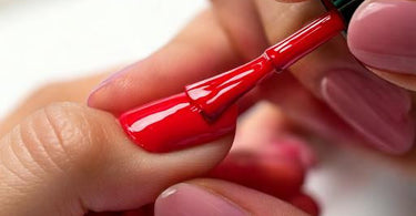 Hand receiving a manicure with red nail polish from Morgan Taylor