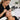 Lash artist applying extensions to client with uneven lash growth using magnifying light and professional tools