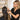 A hairstylist's hands expertly applying a tape-in hair extension weft to a client's hair, showcasing a clean section and professional technique in a modern salon setting.