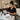A happy massage therapist smiling while looking at a clock, symbolizing stress-free scheduling and effective buffer time management in a spa setting.