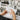 A professional beauty therapist carefully applying lash tint to a client lying down in a spa, with various tint shades visible on a nearby tray.