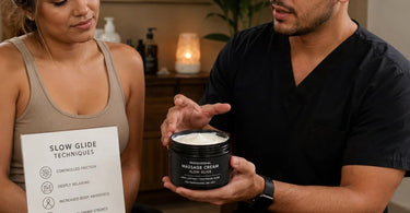 A professional massage therapist applying massage cream to a client's back for a slow glide deep tissue massage technique, featuring the Pure-Ssage Essential Massage Cream product.