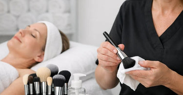 Clean synthetic makeup brushes drying on a white towel with soap and cleaning mat nearby
