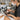 Professional makeup artist cleaning and sanitizing eyeshadow palettes with alcohol spray and tools on a studio table.