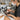 Professional makeup artist cleaning and sanitizing eyeshadow palettes with alcohol spray and tools on a studio table.