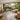 A serene salon space with large glass doors open to a lush outdoor patio, featuring a massage table and stylish decor for seamless indoor-outdoor flow.