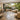 A serene salon space with large glass doors open to a lush outdoor patio, featuring a massage table and stylish decor for seamless indoor-outdoor flow.
