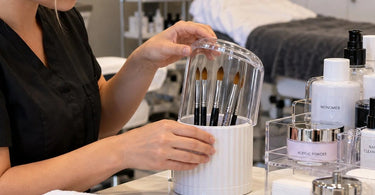 Professional acrylic nail brushes and organized manicure tools at a clean nail salon workstation, illustrating how to protect acrylic brushes from dust between clients
