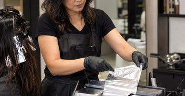 A professional salon color station featuring a stable foil dispenser and neatly organized tools, demonstrating how to keep foil boxes stable during busy color services.