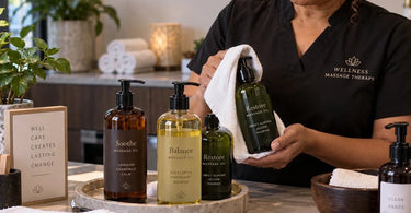 Massage therapist in a treatment room holding a bottle of massage oil with a pump dispenser to prevent slippery hands