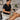 A professional spa therapist applying a body scrub to a client's back using a clean spatula and bowl, demonstrating mess-free layering techniques with premium products.