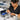 Technician applies lubricating oil to the pivot point screw of professional stainless steel hair shears for maintenance.