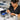 Technician applies lubricating oil to the pivot point screw of professional stainless steel hair shears for maintenance.