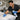 Esthetician cleaning a facial bed in a multi-bed suite with disinfectant spray and fresh linens nearby