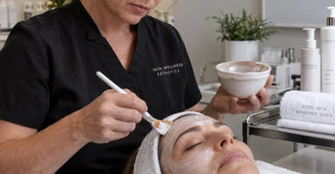 Esthetician applying facial product with headband and barrier cream to protect client hairline during spa treatment