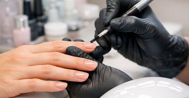 A collage of images for a blog on preventing gel allergies, featuring a nail technician carefully applying gel polish away from the cuticle, a UV lamp curing a nail, and a person applying cuticle oil, all on a soft pink background.