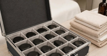 A professional spa therapist carefully places a smooth, black basalt massage stone into a wooden storage box, illustrating how to prevent chips and cracks, with a focus on proper storage techniques for massage stones.