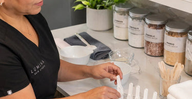 A neatly organized back bar in a professional spa, featuring labeled jars, dedicated storage for product scoops, and hygienic containers, showcasing a system to prevent scoops from getting lost.