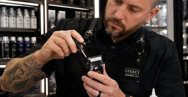 Close-up of a professional's hand adjusting the tension screw on a hair clipper for optimal performance and maintenance.