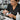 Technician cleaning a professional electric foot file roller with a brush and disinfectant spray on a salon counter.